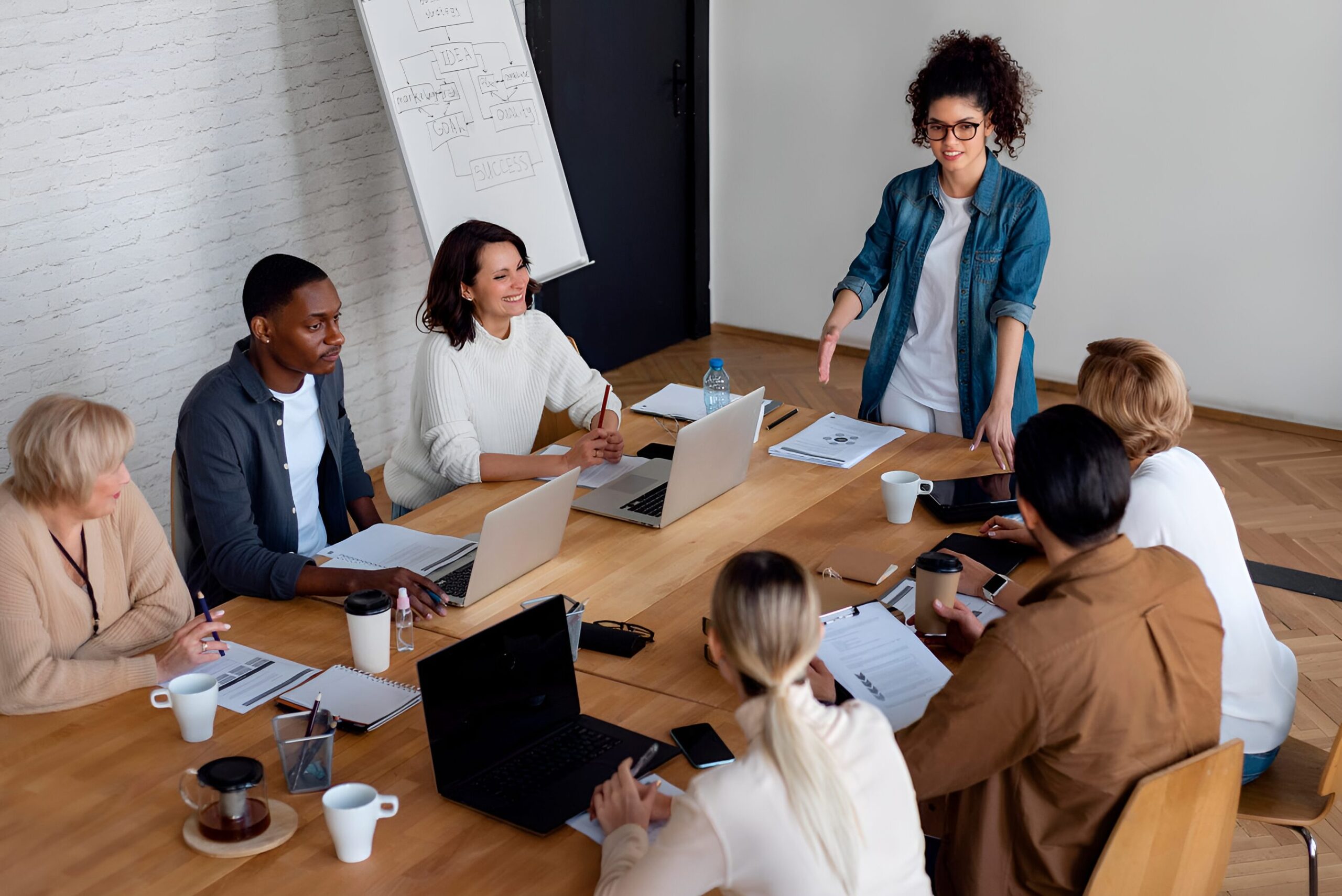 Business team in a casual meeting setting, woman standing and presenting.